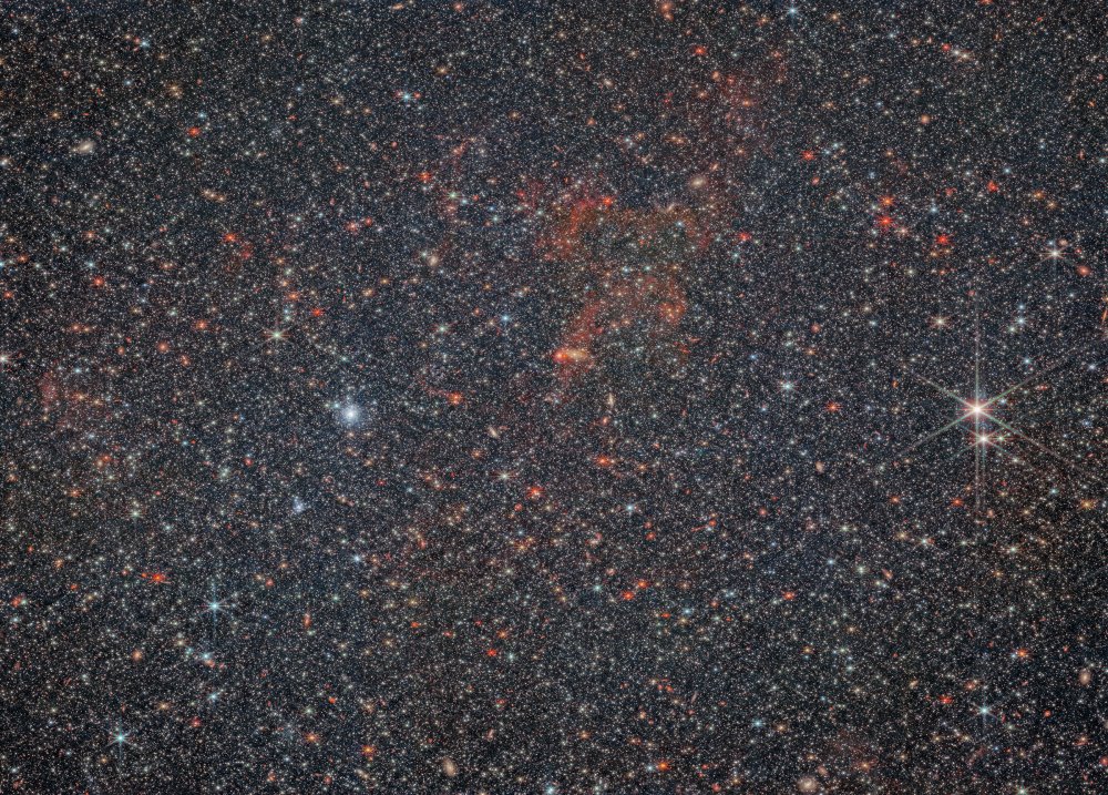 一片极为浓密的星场完全充满了微小的星星。许多各种形状和大小的星系隐藏在星星后面可见。中心有一些淡淡的、轻薄的暗红色气体。几颗成像的星星比其他星星稍大,具有可见的衍射条纹。右侧有两个特别大亮的前景星。