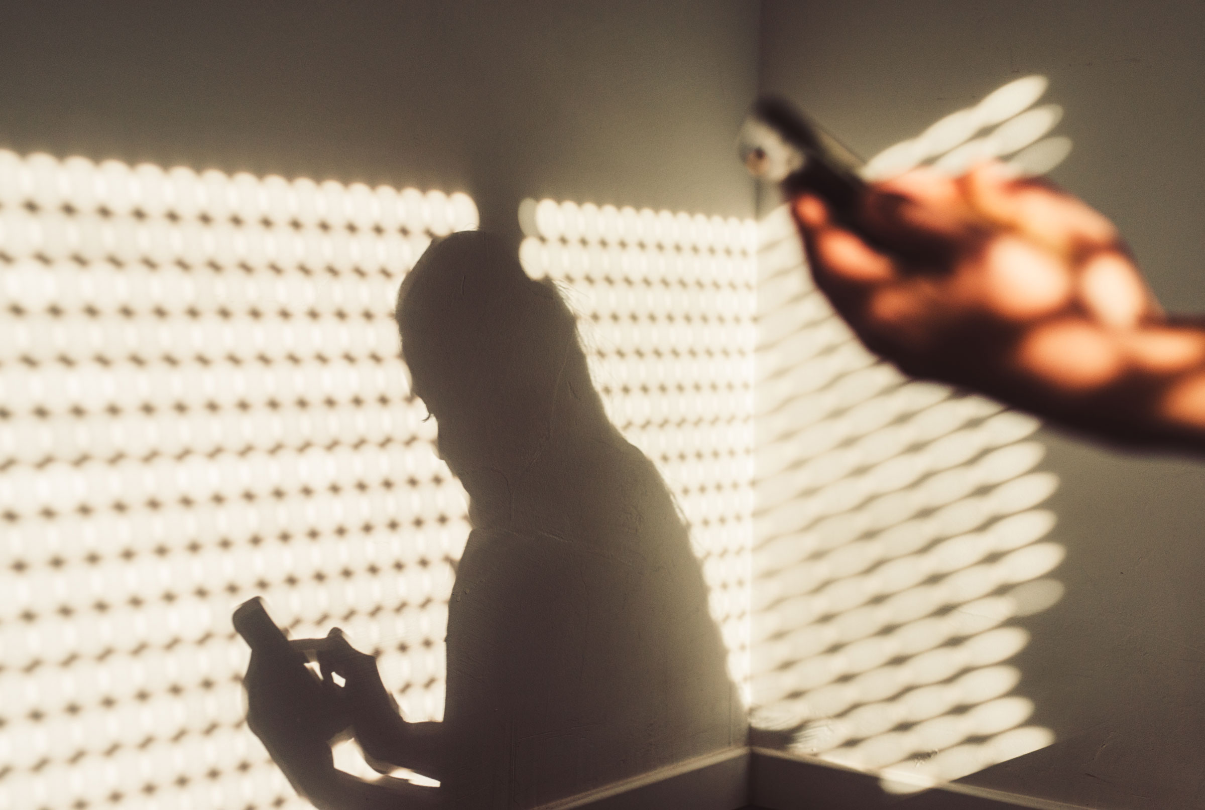 一名女性使用智能手机的影子