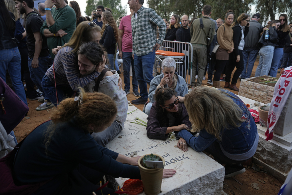 Friends that attended the funeral of 26-year-old Alon Shamriz mourn over the grave of a victim of the Oct. 7th attack buried in the same cemetery in Kibbutz Shefayim, Israel, Sunday Dec. 17, 2023. 