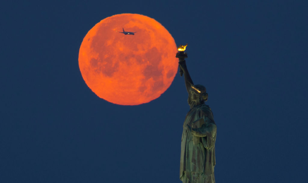 Full Strawberry Moon Sets Behind the Statue of Liberty in New York City