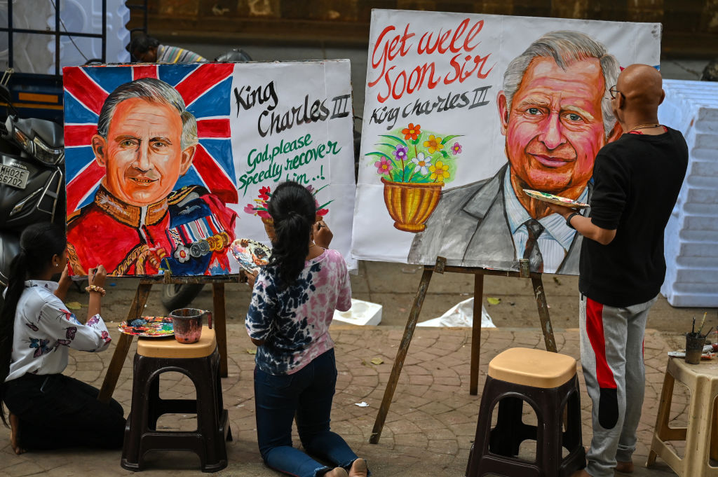 Một nghệ sĩ (R) và sinh viên thêm những nét chấm hồ cho bức tranh chân dung của Vua Charles III của Anh để chúc ông mau khỏi bệnh, bên ngoài một trường nghệ thuật ở Mumbai.