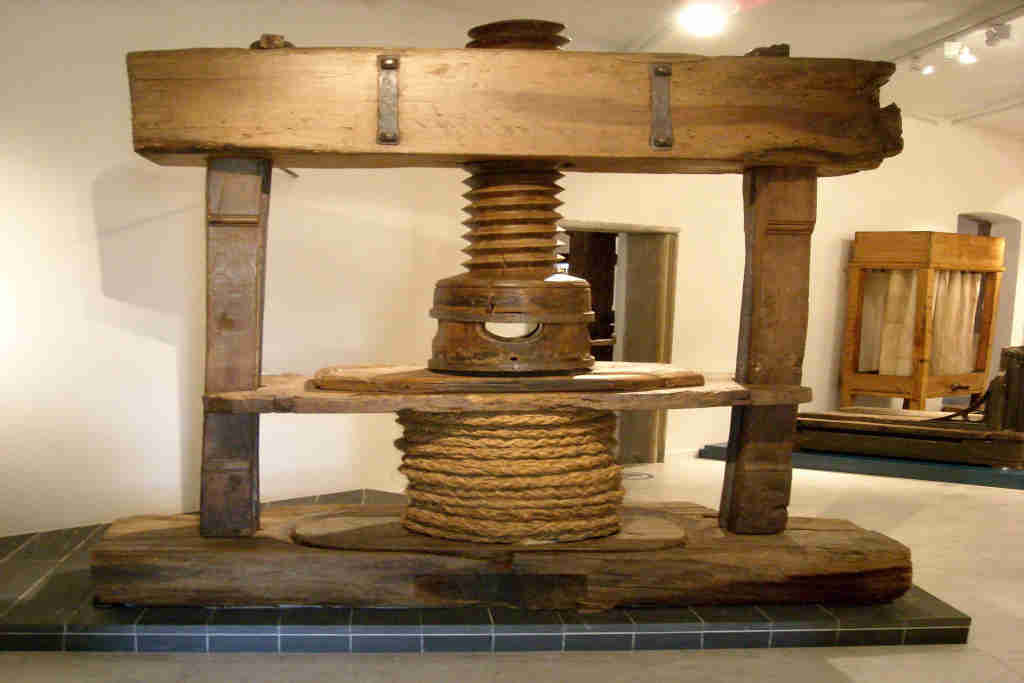 Vieux pressoir en bois du Moyen âge avec un énorme axe central en bois avec pas de vis taillé dans la masse pour mettre sous pression les scourtins garnis de pâte d’olive afin d’extraire l’huile