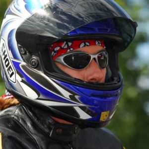 A portrait shot of a female motorcycle rider wearing a full face helmet. Kath is wearing a Original Buff® as helmet liner. She is also wearing a motorcycle leather jacket and sunglasses. Source: Kath Salotti © permission to use on our websites