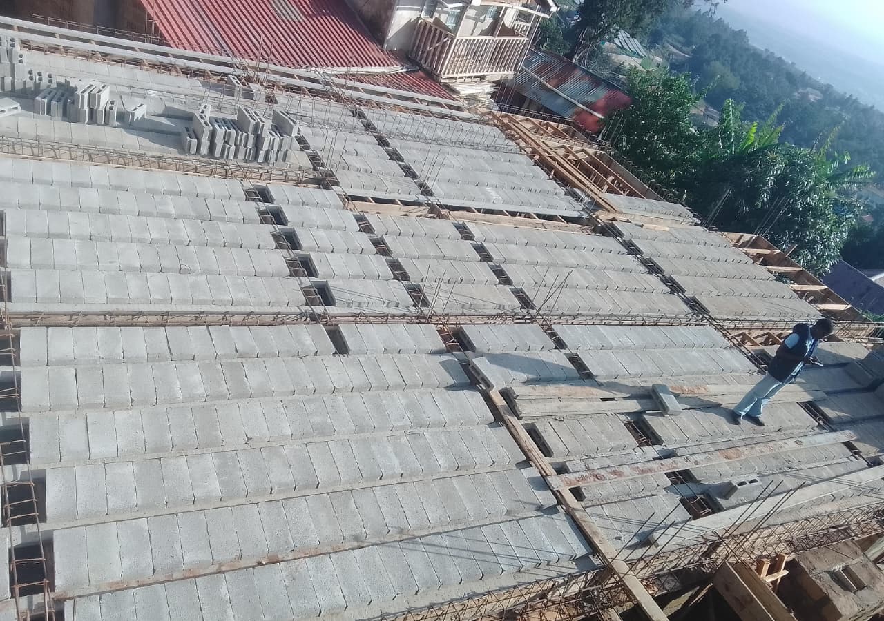 Reinforced concrete roof slab formwork under construction with a worker walking across it