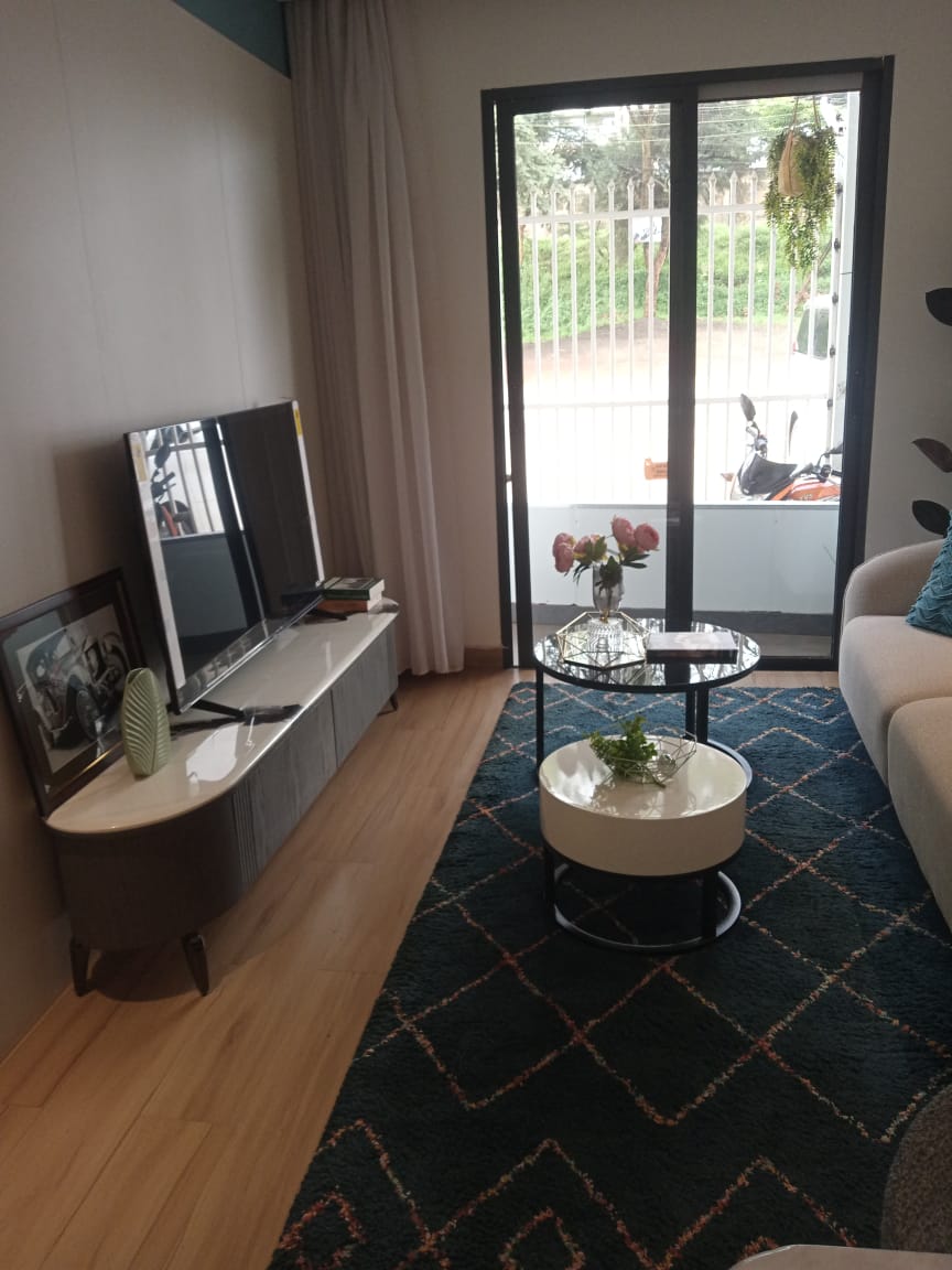 Living room with TV console and coffee table Living room with a low TV console, glass coffee table, patterned rug and view of the balcony