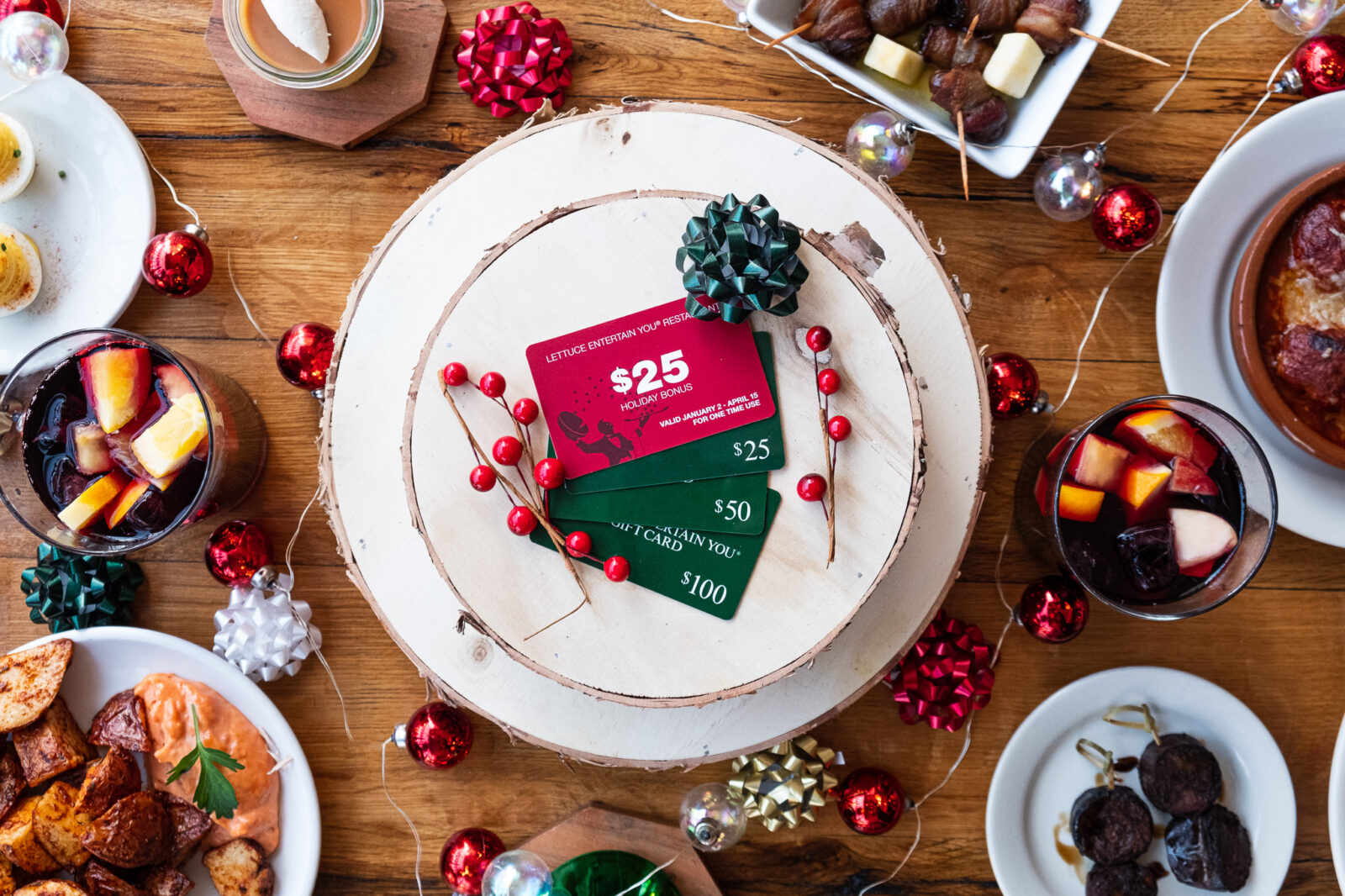 Lettuce Entertain You Holiday Gift Cards surrounded by holiday decorations and Cafe Ba-Ba-Reeba! classic dishes for the Free $25 Holiday Bonus Gift Card Campaign