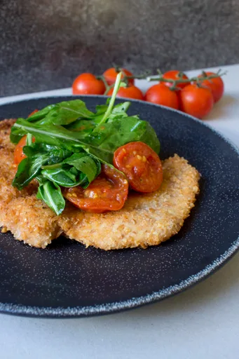 Milanesa de pollo con tomates cherry salteados