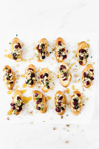Crostini de queso azul, nueces, arándanos rojos y miel
