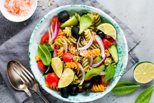 Pasta fusilli estilo ensalada griega vegana con lima, albahaca y aceitunas