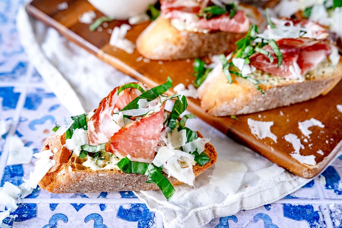 Crostini mit Kräutercreme, Coppa, Parmesan und Basilikum