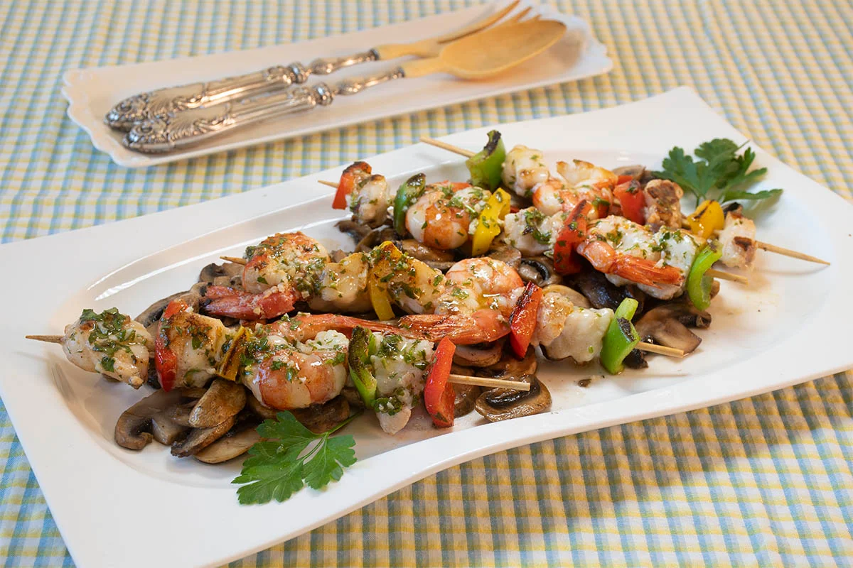 Brochetas de rape y langostinos sobre champiñones
