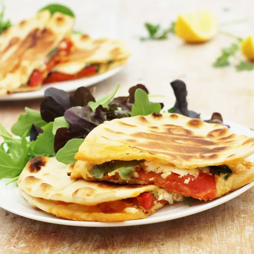Panes planos tostados con feta, pimientos asados y harissa