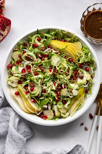 Ensalada de coles de Bruselas finamente cortadas con granada y vinagreta balsámica