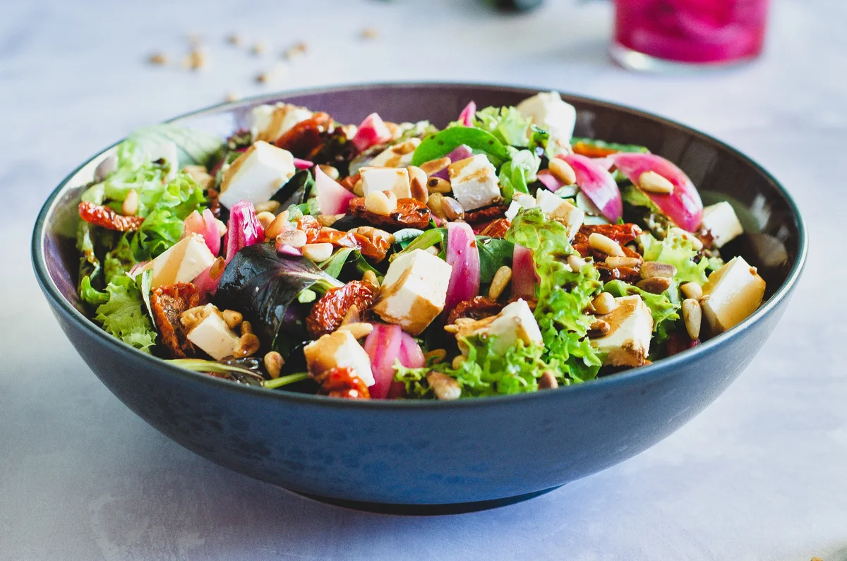 Salat mit eingelegten roten Zwiebeln und gerösteten Tomaten