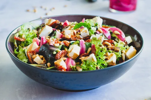 Salat mit eingelegten roten Zwiebeln und gerösteten Tomaten