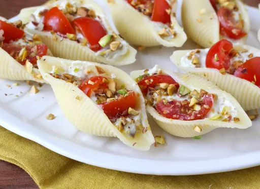 Conchiglioni umpluți, serviți reci, cu stracciatella, fistic, roșii cherry și lămâie