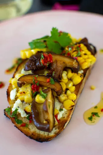Tostada vegetariana con setas, maíz y queso de cabra