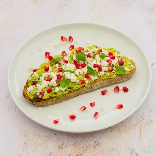 Tostada de aguacate con queso feta y granada