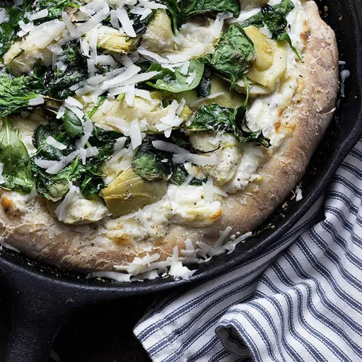 Pizza de espinacas y alcachofas en sartén de hierro fundido