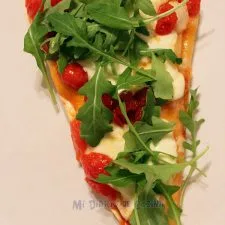 Pizza con mozzarella, tomate cherry caramelizado y arúgula