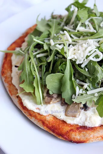 Pizza con ricotta, cebolla caramelizada, champiñones y rúcula
