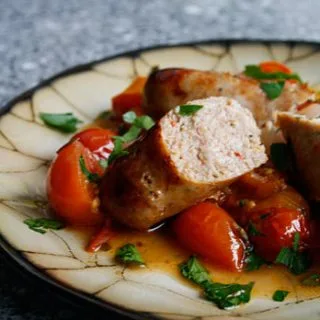 Salchichas asadas con tomates, pimientos y cebollas