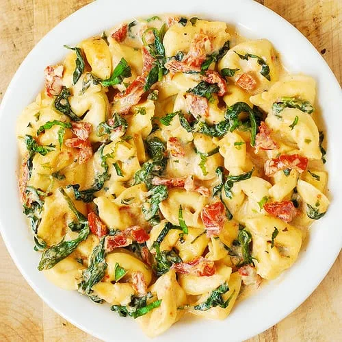 Tortellini cremosos con mozzarella, tomates secos, albahaca y espinacas