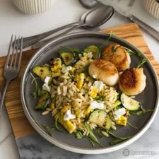 Ensalada de maíz asado, calabacín y orzo con queso de cabra y vieira marcada