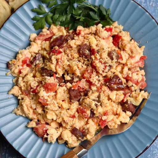 Huevos revueltos con salchicha griega, tomates y queso