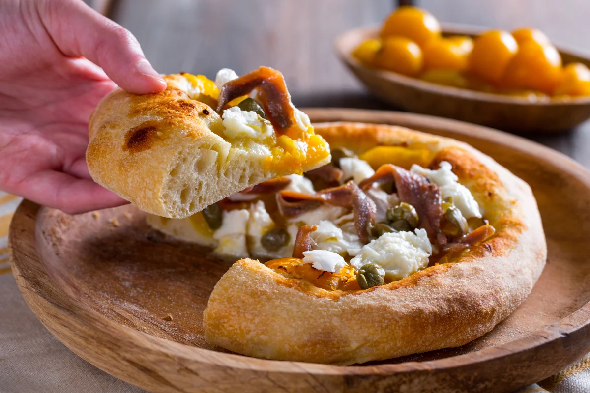 Pizza con tomatitos amarillos, anchoas y alcaparras
