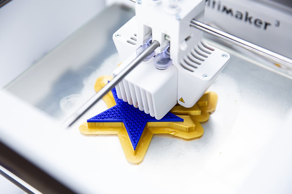 Photo of a 3-D printer creating a blue and gold star