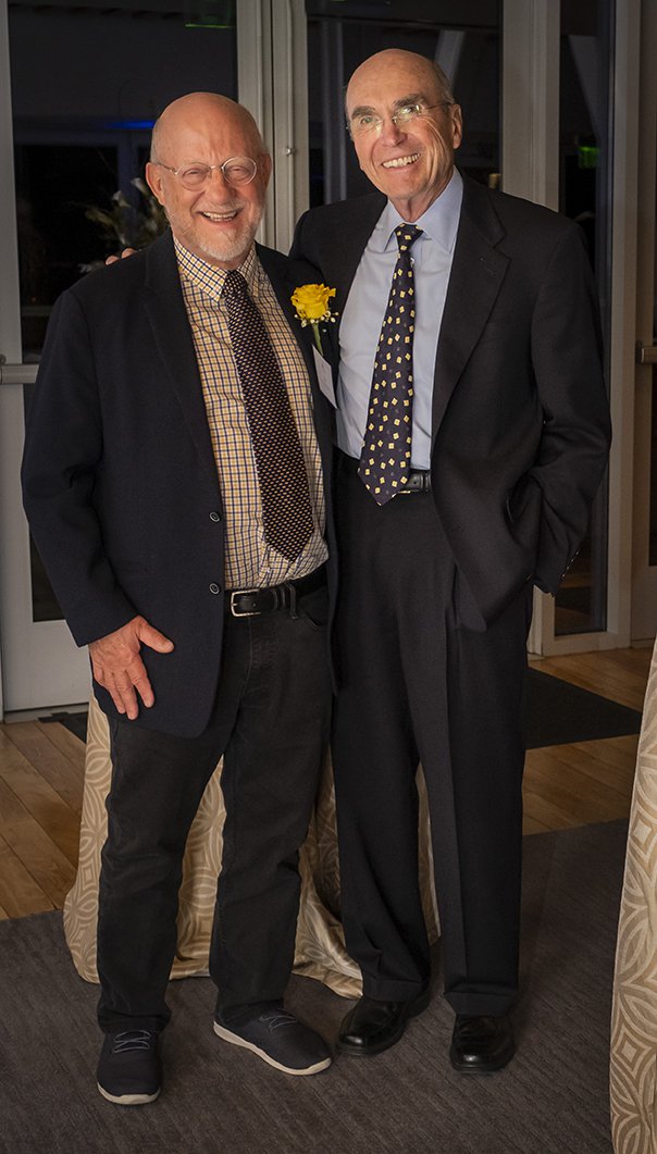 Photo of two guests in jackets and ties standing together as they smile at the camera