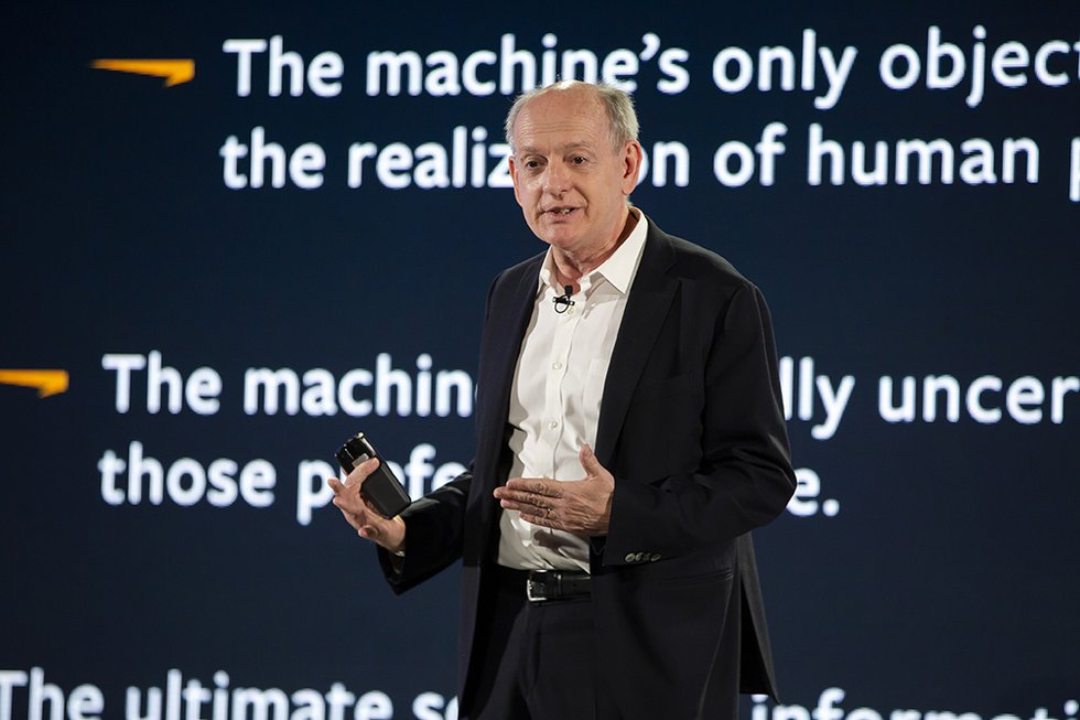 Photo of a speaker onstage with text about AI onstage