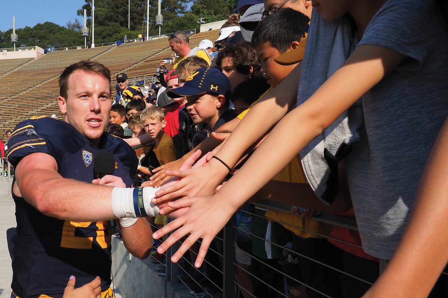 Photo of Cal football player Patrick Laird ’18 in uniform greeting enthusiastic young readers.