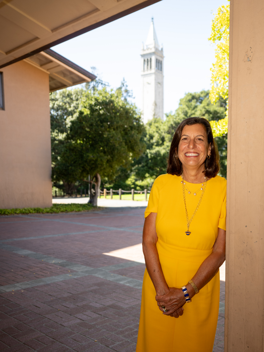 Bettina is leaning against a courtyard column in a yellow dress with the Campanile in the background.