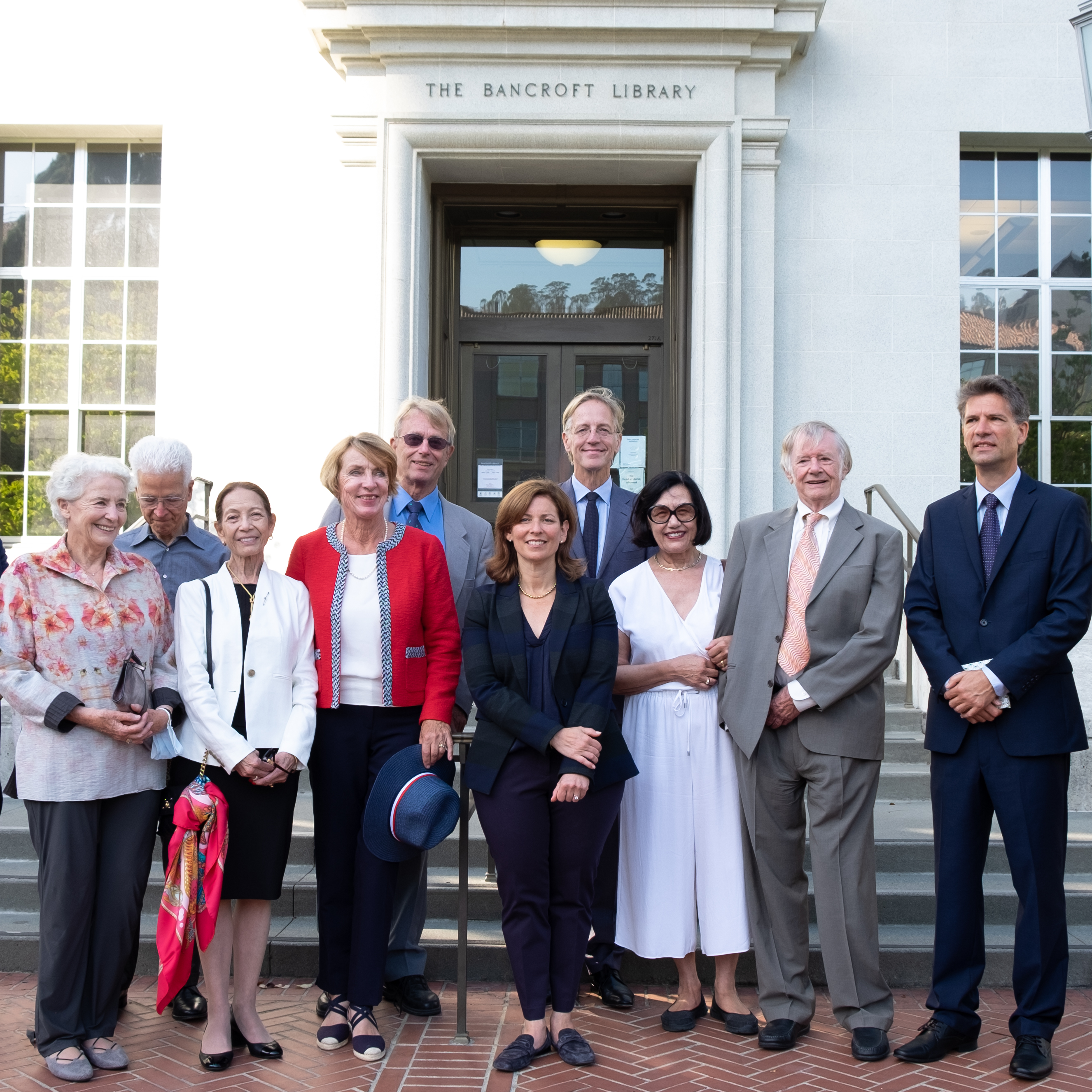 Photo of 10 people standing and smiling in front of the entry to Bancroft Library.