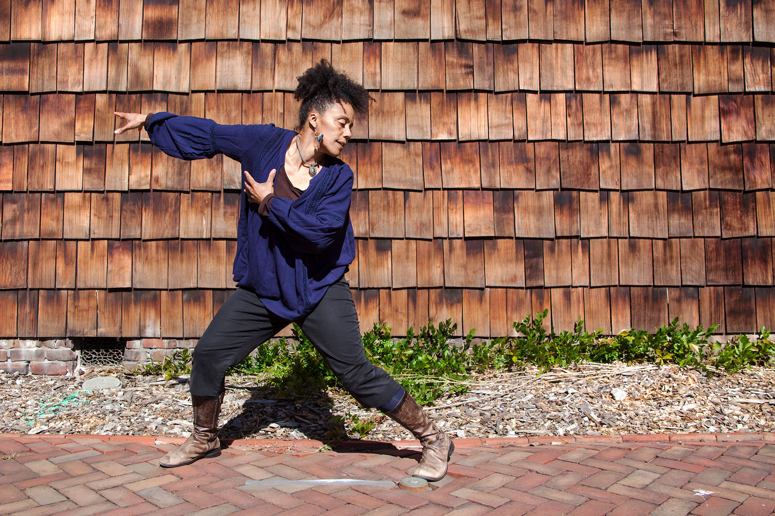 Photo of Tabor-Smith dancing in front of a shingled wall.