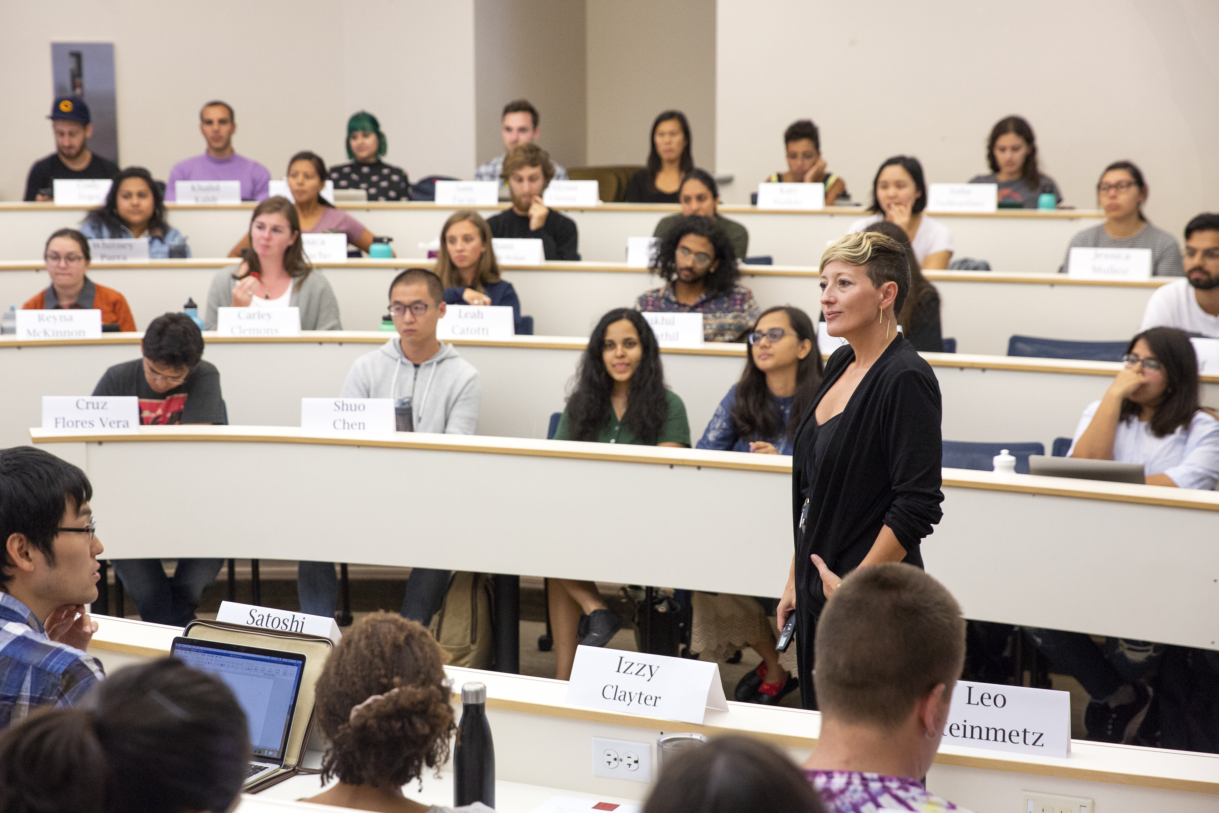 Photo of a teacher in half profile, listening intently to one of their students in class