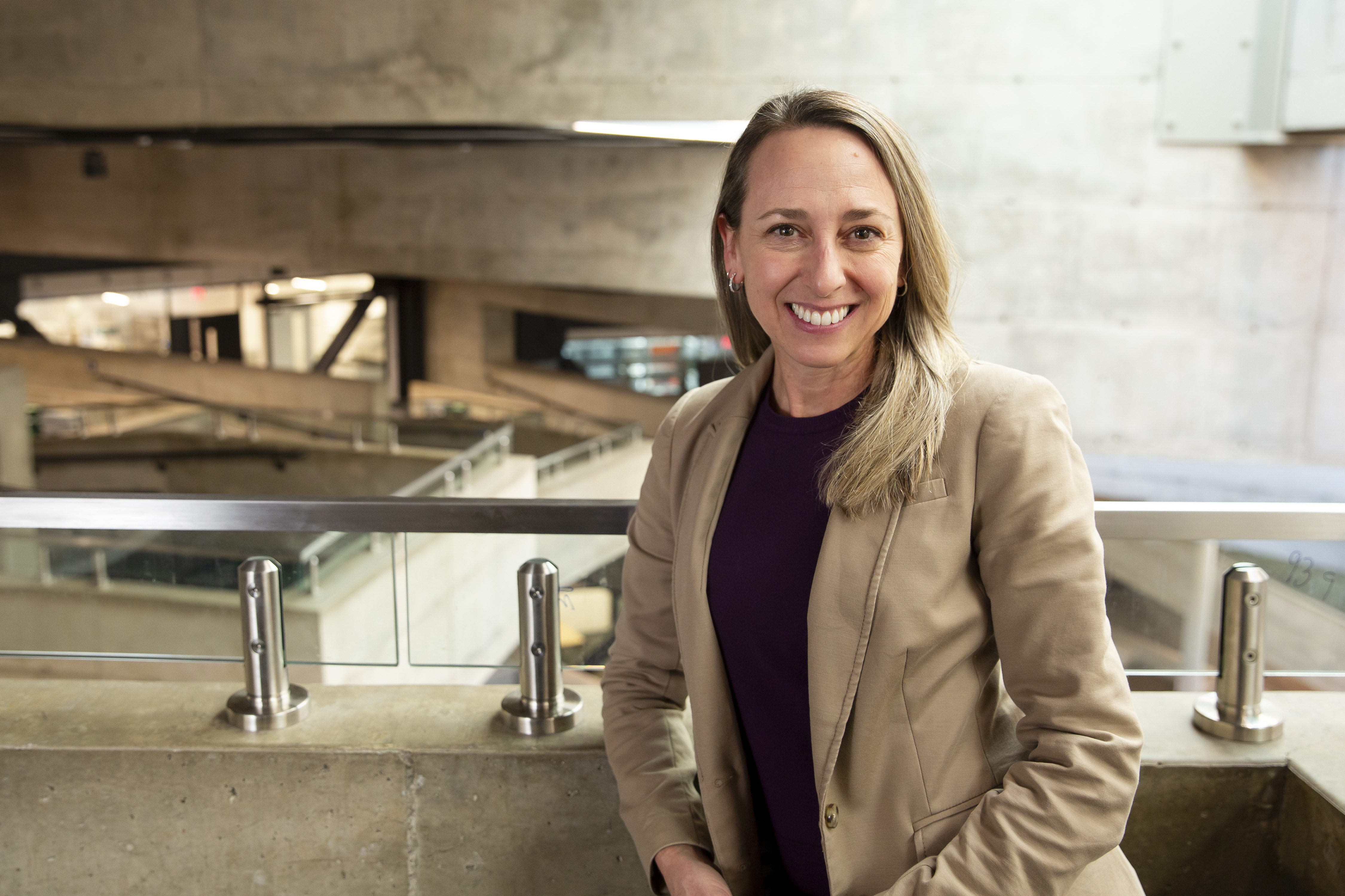 Photo of a woman smiling at the camera, the building's indoor balconies visible behind her.