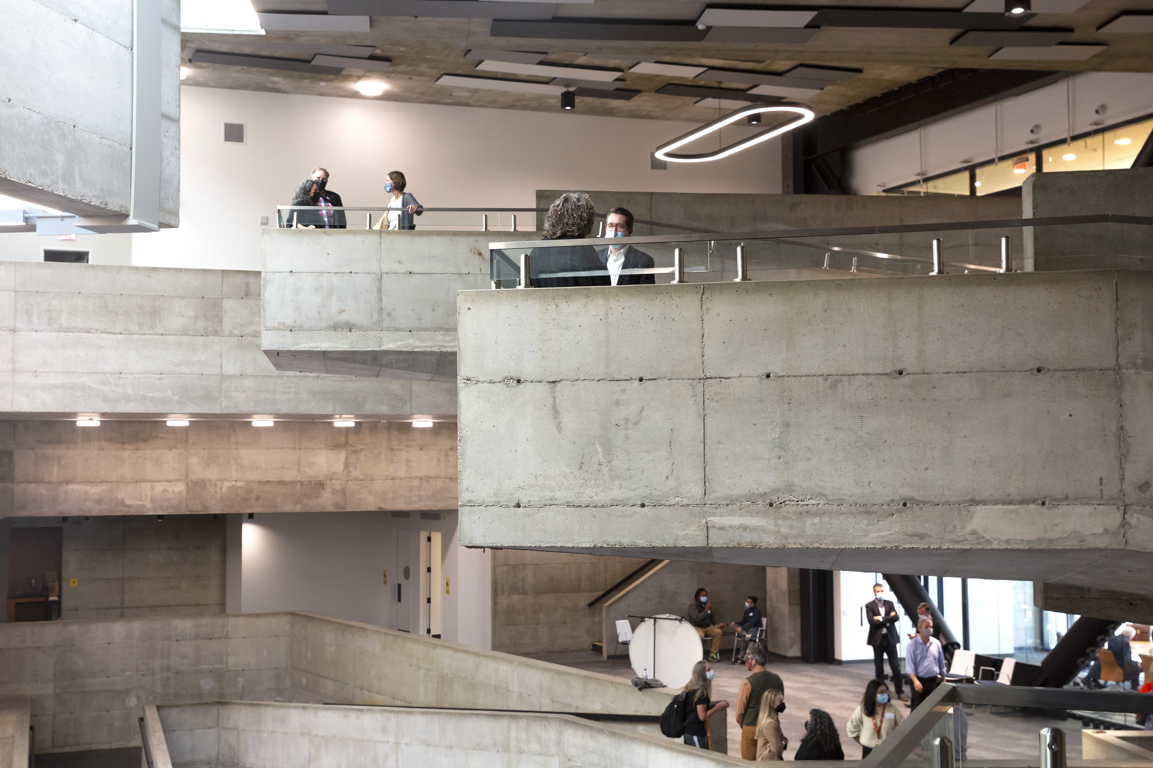 Wide photo of the building's indoor balconies, with people gathered in small groups on all three levels.