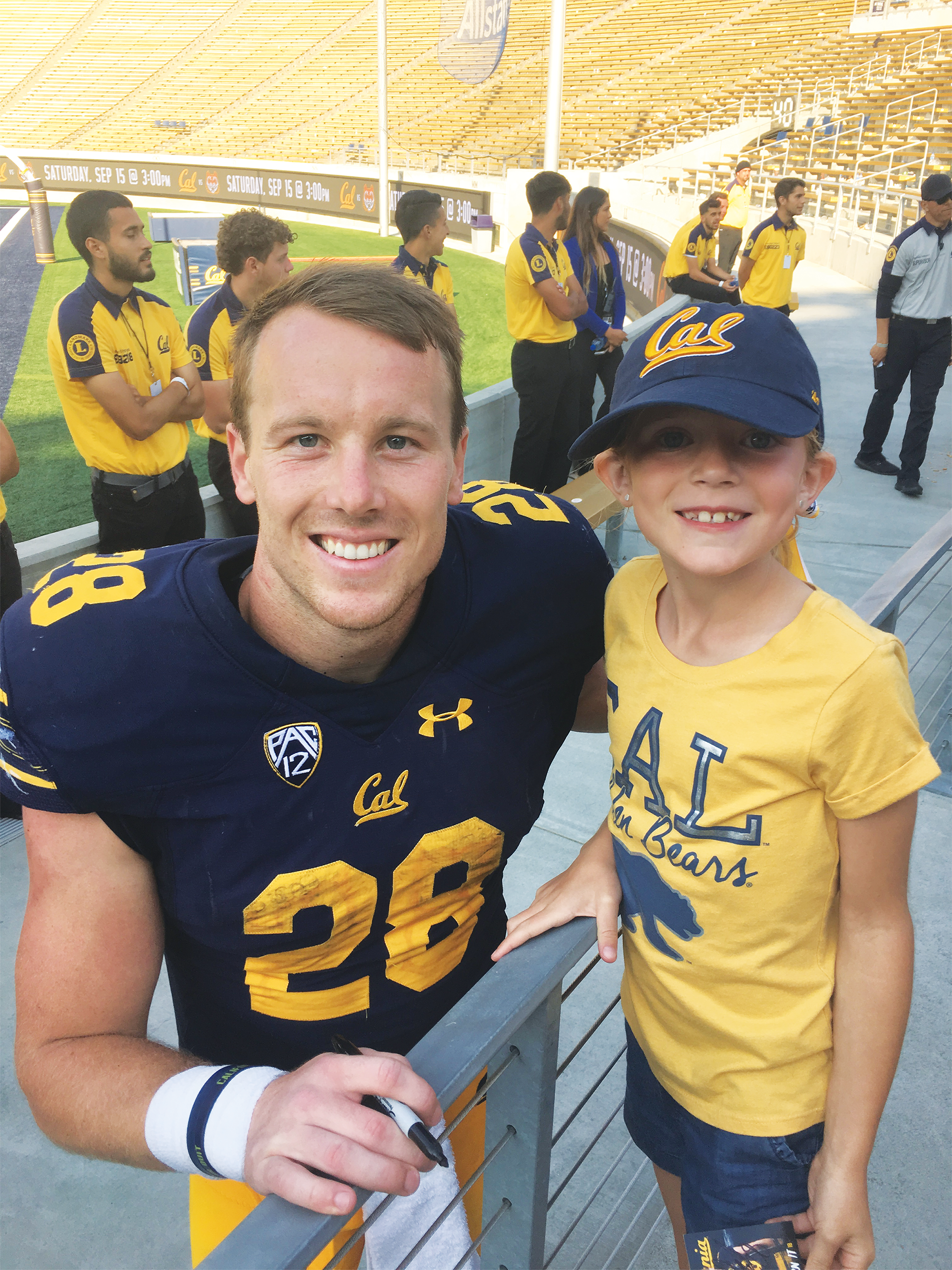 Photo of a grinning seven-year-old Andie Wiskerson in Cal gear meeting football star Patrick Laird '18.