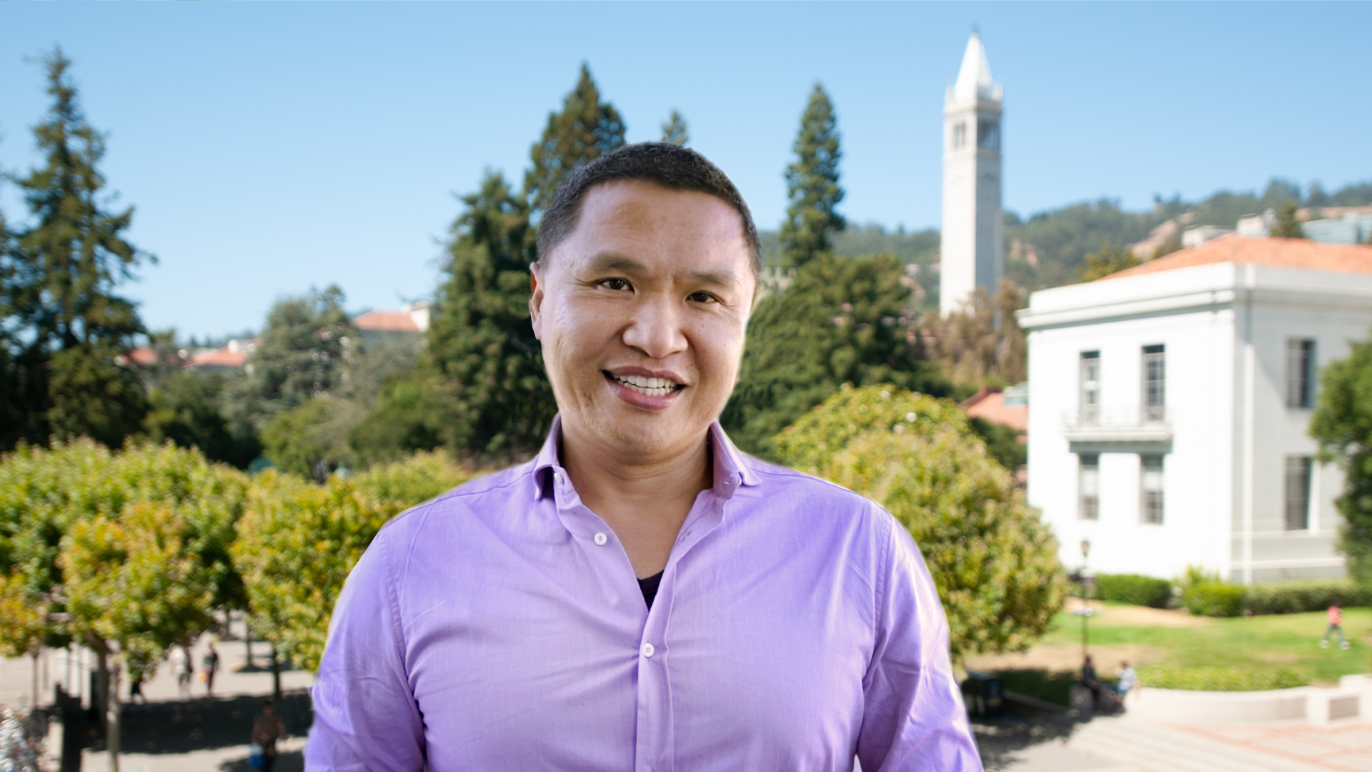 Photo of Charles in a lavender shirt, standing on a deck above Sproul Plaza with the Campanile and Sproul Hall in the background.