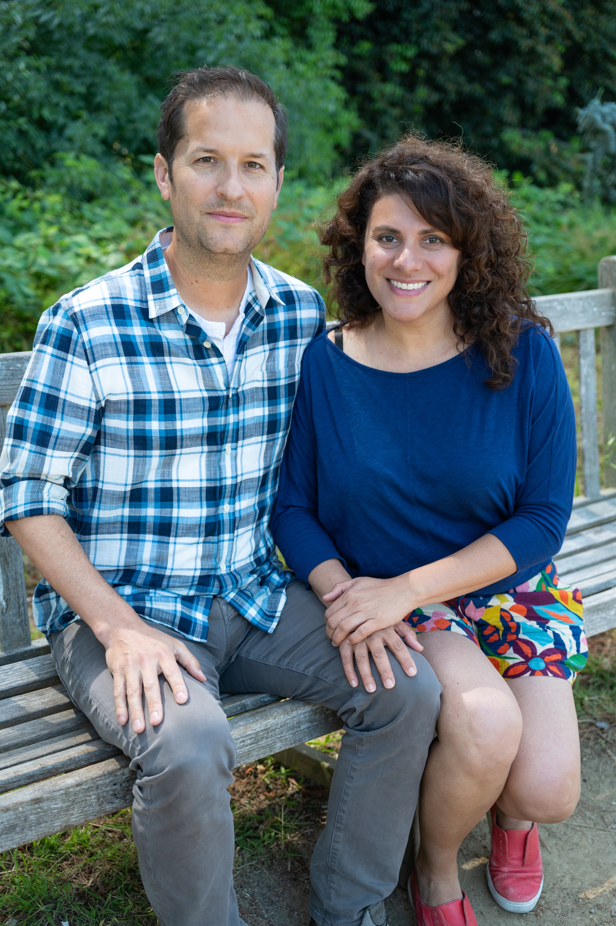 Photo of Chris with his arm around Sara and her hands crossed on his knee, sitting on a wooden bench.