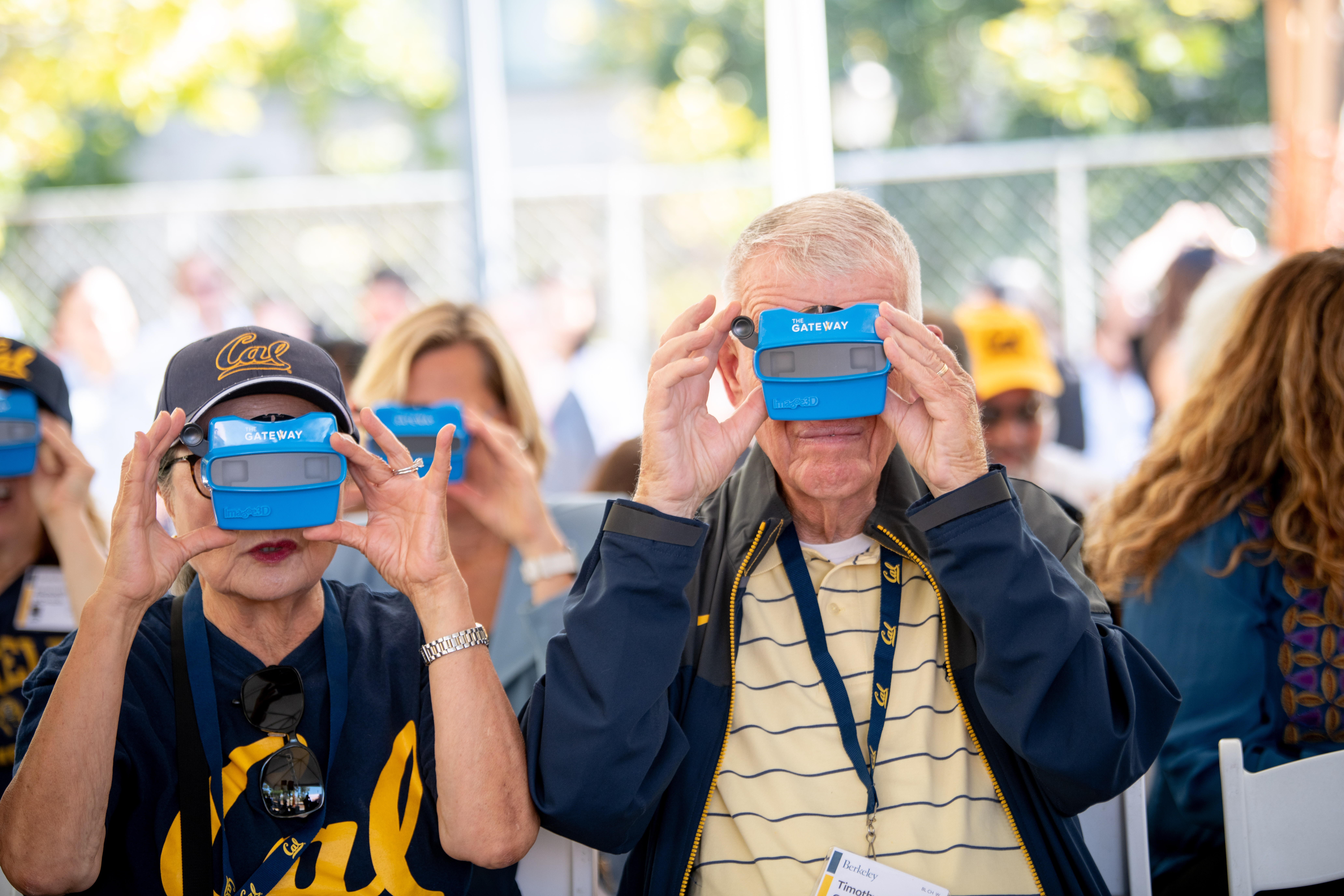 Photo of a woman in navy blue Cal script t-shirt and a man in a yellow and blue striped shirt looking through blue ViewMasters.