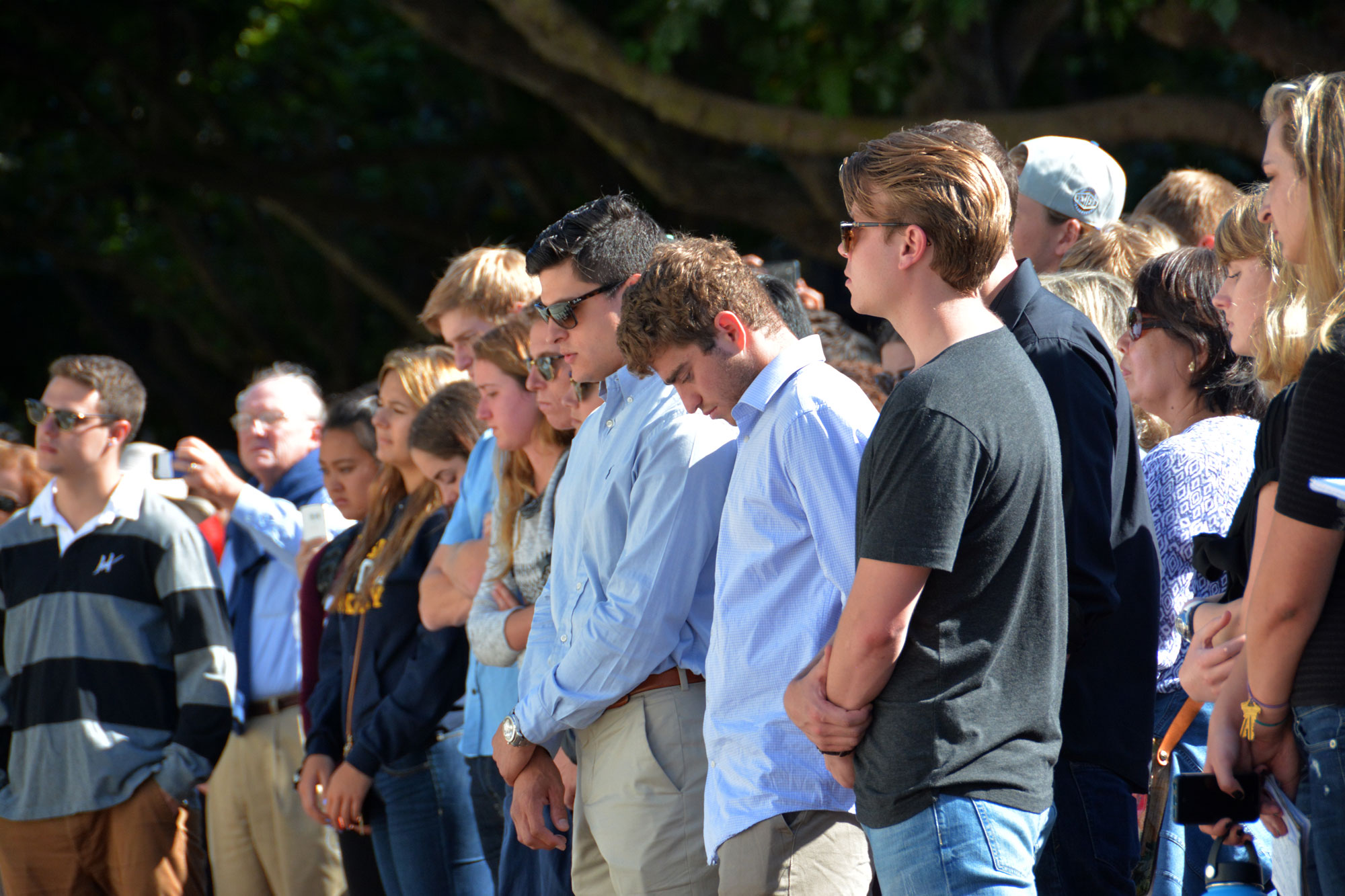 Photo of members of the Cal community at a memorial service, many with their heads bowed down.