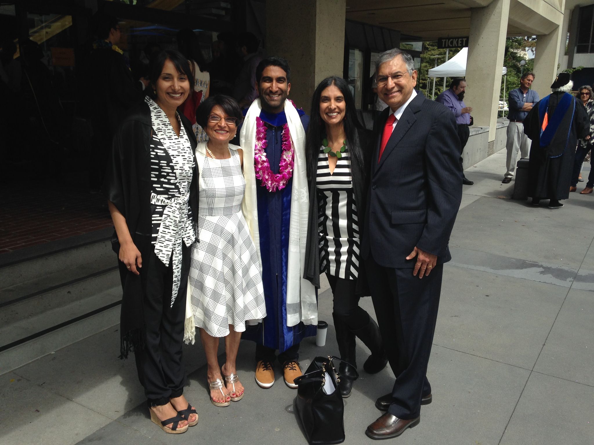 Color photo of Sam in graduation robes, center, surrounded by his parents and sisters