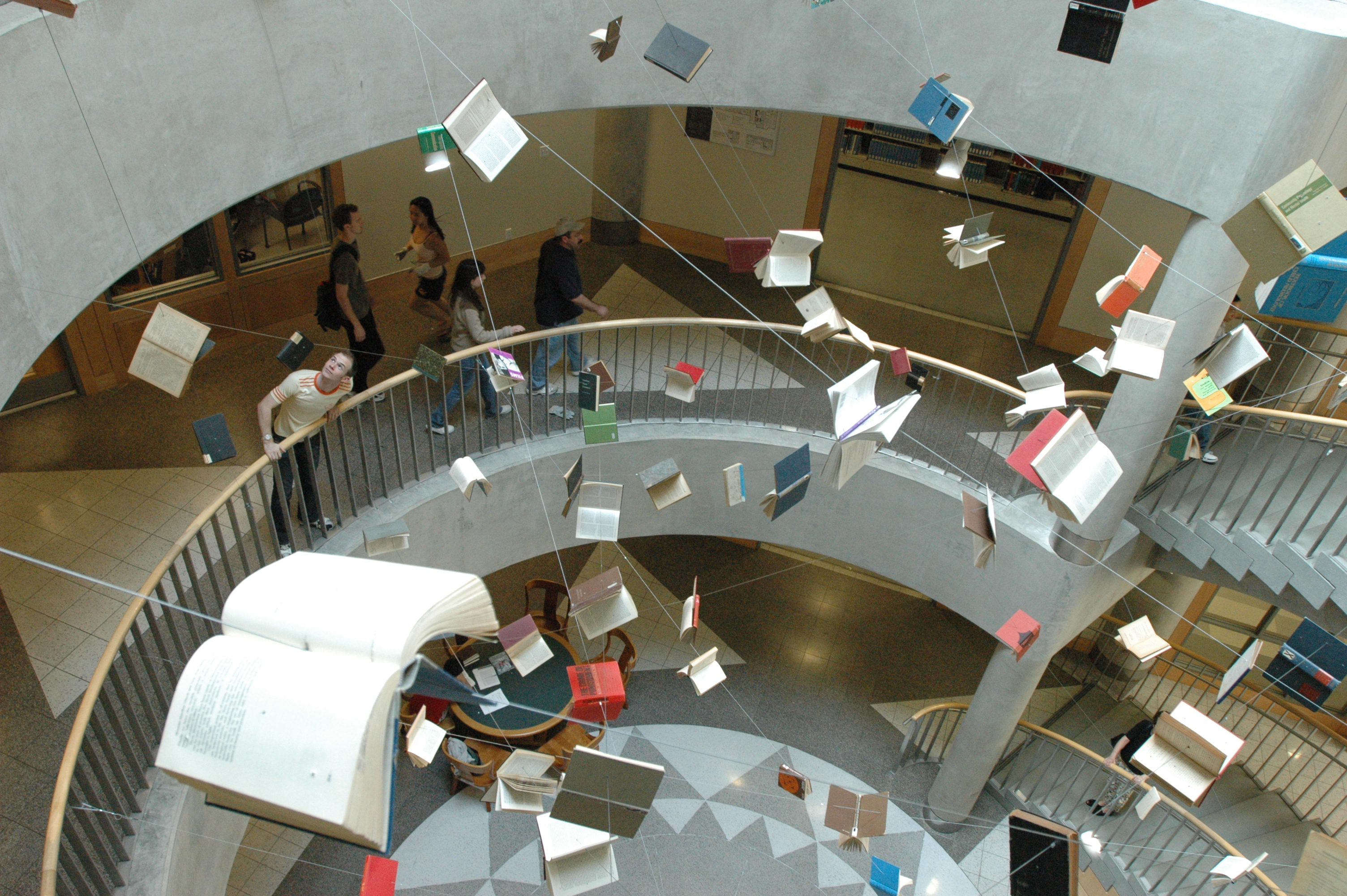 Photo of books seeming to fly through the staircase atrium leading down to Gardner stacks