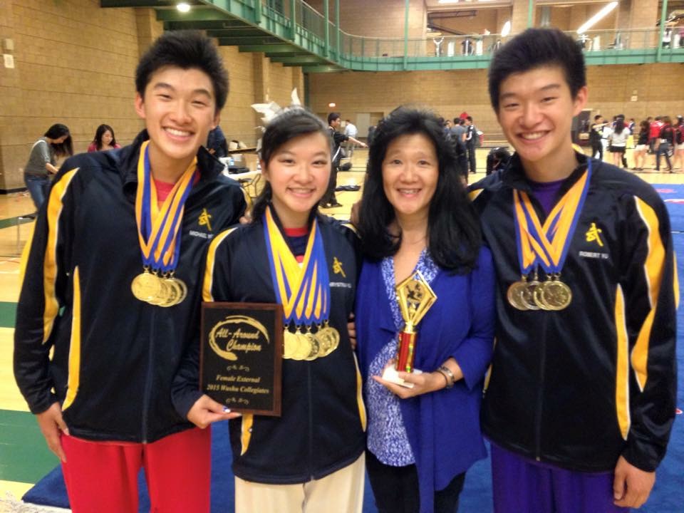 Photo of the Yu children with their mother donning medals around their necks and holding awards.