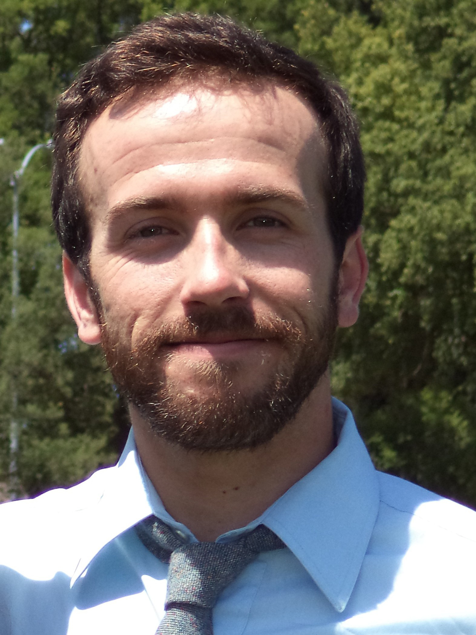 Photo of Greg smiling in front of trees