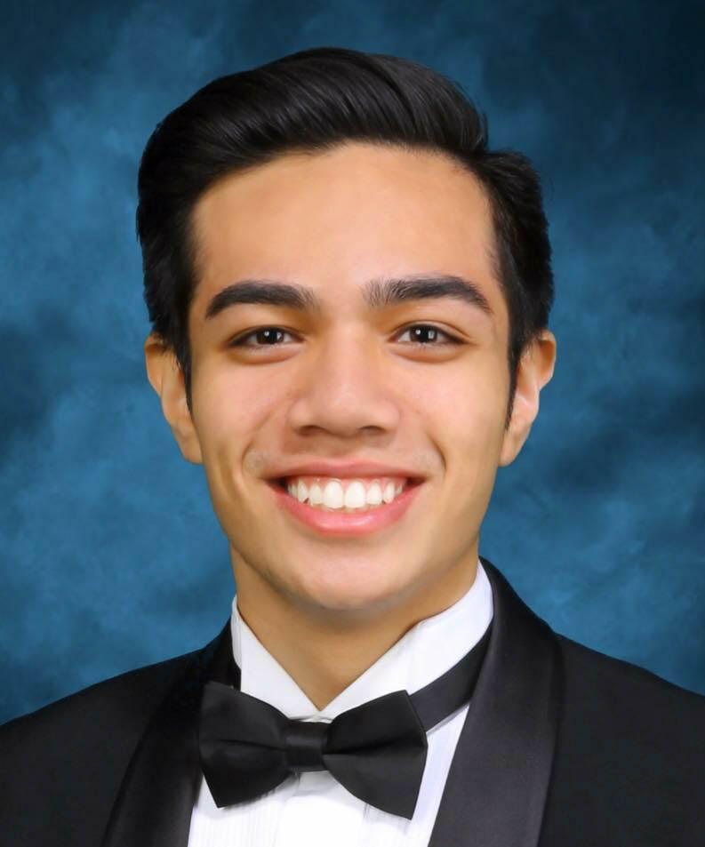 Color headshot photo of a smiling Hitesh in a tuxedo, with a blue background behind them